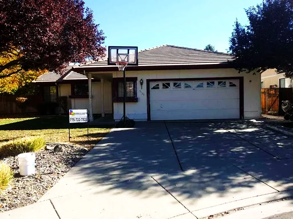 Tan stucco house with white garage doors after repaint