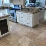 Modern kitchen with white cabinetry, granite countertops, stainless steel appliances, and tile flooring with an island and breakfast bar
