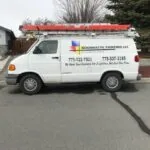 White work van with red roof rack parked in driveway, displaying painting company contact information and logo on side